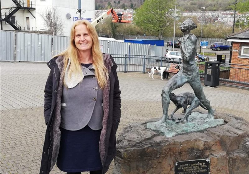 Beth Winter standing next to the Guto statue at Rhos Square in Mountain Ash