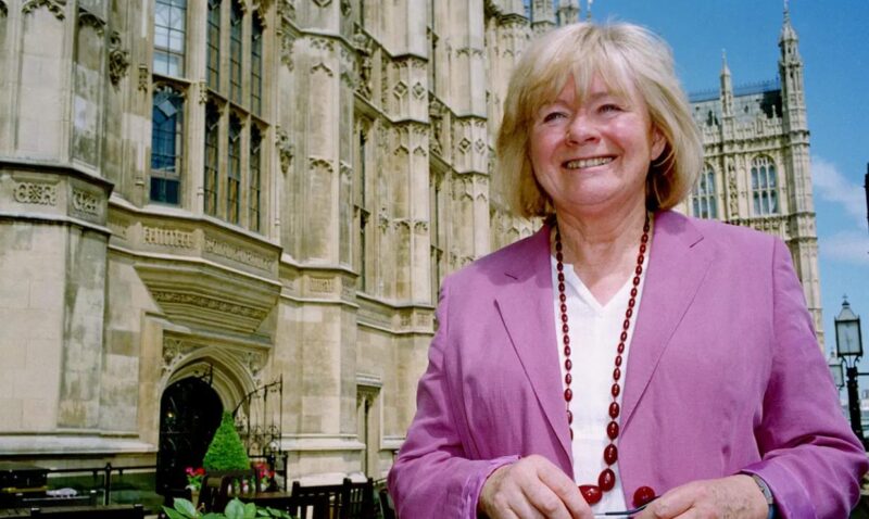 Ann Clwyd walking outside parliament in a pink blazer.